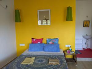 een slaapkamer met een bed met een gele muur bij Blue Moon Guest House in Mahabalipuram
