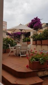 une terrasse avec un parasol, des chaises et des fleurs dans l'établissement Villa Liberty, à La Maddalena