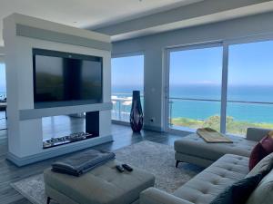 a living room with a television and a couch and chairs at The BlueHouse in Mossel Bay