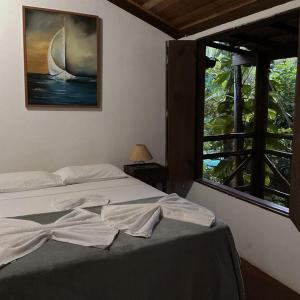 een slaapkamer met een bed met een schilderij aan de muur bij Pousada Guaiamum in Itacaré