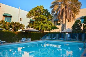 uma piscina com cadeiras e guarda-sóis ao lado de um edifício em Al CORNICHE HOTEL em Sharjah