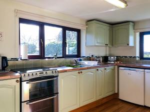 a kitchen with green and white cabinets and windows at Our Snug in Riccall