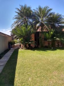 a yard with palm trees in front of a house at Casa na Praia do Lázaro em Ubatuba/SP in Ubatuba