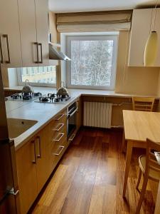 a kitchen with wooden floors and a large window at Comfortable Stay in Siauliai in Šiauliai