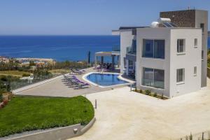 a large white house with a swimming pool and the ocean at Elite Sea View Villa in Pomos