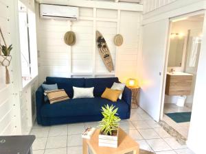 een woonkamer met een blauwe bank en een tafel bij Lagon Sainte-Anne : au calme et à 2 pas des plages in Sainte-Anne