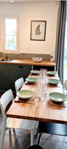 une table en bois avec des assiettes et des verres verts dans l'établissement Maison le Havre de la Gachère, 2 chambres, 2 salles d'eau, parking privé et jardin, à Brem-sur-Mer