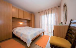 a bedroom with a bed and a chair and a window at App&Rooms Anica Kampor in Kampor