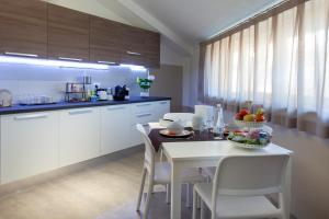 a kitchen with a white table and white chairs at Bed & Bike in Aulla