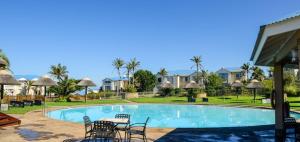 uma piscina num resort com cadeiras e uma mesa em The BlueHouse em Mossel Bay