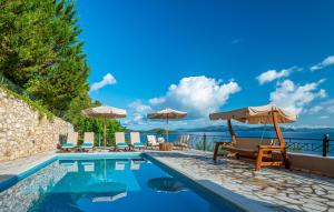 a swimming pool with chairs and umbrellas next to the ocean at Meganisi Villas in Spartokhórion
