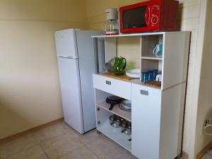 a kitchen with a white refrigerator and a red microwave at VILLA AICHY in Rabi