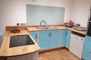 una cocina con armarios azules y fregadero en Traditional coach house in rural private estate., en Yeovil