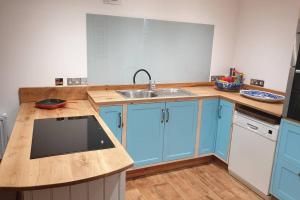 una cucina con armadi blu e lavandino di Traditional coach house in rural private estate. a Yeovil