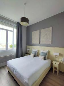 a bedroom with a large white bed with two pillows at Les Embruns in Trouville-sur-Mer