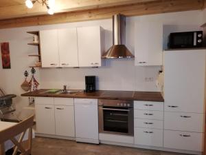 cocina con armarios blancos, fregadero y nevera en Ferienwohnung Grabenhäusl, en Ruhpolding