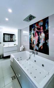un ampio bagno bianco con vasca e TV di Casa Varful Cu Dor a Sinaia