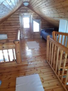 a room with a bed and a staircase in a log cabin at Koivuranta in Pihtipuoas