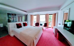 a bedroom with a large white bed and a flat screen tv at Casa Varful Cu Dor in Sinaia