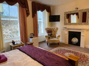 1 dormitorio con 1 cama, 1 silla y chimenea en Station House, Dartmoor and Coast located, Village centre Hotel en South Brent