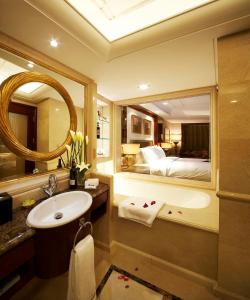 W łazience znajduje się łóżko, umywalka i lustro. w obiekcie Dynasty International Hotel Dalian w mieście Jinzhou