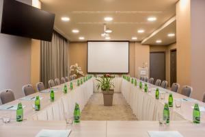 a conference room with long tables and chairs and a screen at Hotel AMI Budva Petrovac in Petrovac na Moru