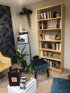 a living room with a book shelf filled with books at Le Regina Hôtel et restaurant Canet-plage in Canet-en-Roussillon