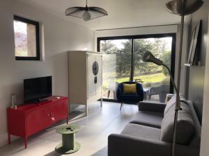 ein Wohnzimmer mit einem Sofa und einem TV in der Unterkunft Dans la Pouncho d’Agast in Millau