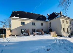 uma grande casa branca com neve no chão em FarmHouse Eckartsberg im Zittauer Gebirge - Ferienwohnung mit 2 Schlafzimmern, Terrasse und WALLBOX em Mittelherwigsdorf