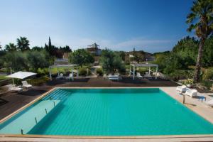 a large swimming pool with chairs and umbrellas at Masseria La Tofala benessere & SPA in Copertino