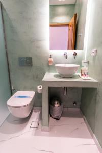 een badkamer met een wastafel, een toilet en een spiegel bij Tinos Koralli in Tinos Town