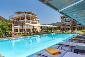 a swimming pool with lounge chairs and a building at Anilio Plaza in Zacharo