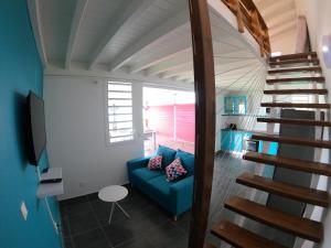 sala de estar con sofá azul y escalera en Gîte Passion Kréyol, Vue mer et montagne, SPA privé en Vieux-Habitants
