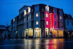 un bâtiment avec des lumières rouges et violettes dans une rue dans l'établissement Hotel Helin Central, à Craiova