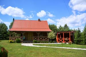 a small house with an orange roof on a field at Domek JEZIORACZEK in Urowo
