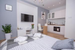 a white bedroom with a large bed and a kitchen at Apartamenty AP 10 in Częstochowa