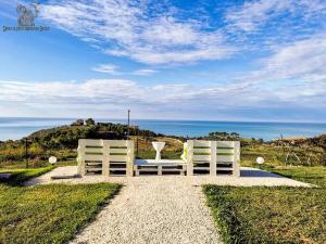 dos sillas blancas sentadas en un camino de grava mirando al océano en B&B L'EDEN DI CAPO BIANCO en Montallegro