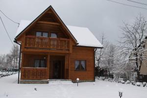 a wooden house with a deck in the snow at Chatka z Góralskim Klimatem in Żywiec