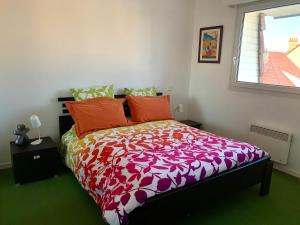 Ninou Cap Sud, terrasse vue mer, appt lumineux 66m2 في ويميريوكس: غرفة نوم مع سرير مع لحاف ملون