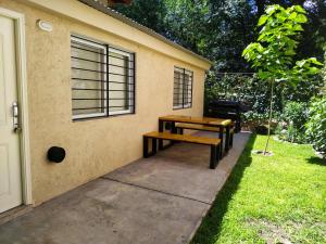 ein Picknicktisch und eine Bank neben einem Haus in der Unterkunft RINCÓN SERENO... Un lugar para disfrutar.... in Villa General Belgrano