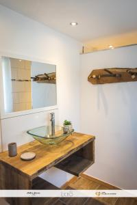 een badkamer met een glazen wastafel en een spiegel bij Le Nid Montagnard in Aucun