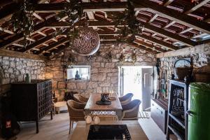 a room with a table and chairs and a stone wall at Nera Etwa House in Lovorje