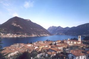 a town in front of a body of water with mountains at Uliveto in Sulzano