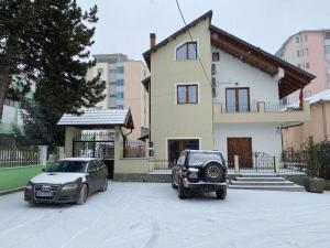 two cars parked in front of a house in the snow at Guesthouse Tershana in Peshkopi