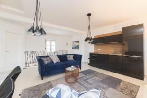 a living room with a blue couch and a kitchen at Apartment Ema in Zadar
