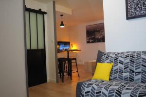uma sala de estar com um sofá e uma almofada amarela em Le Faubourg-Raines - Chaleureux studio à 5mn de la gare em Dijon
