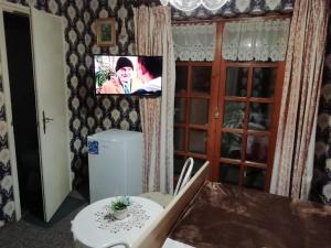 a room with a table and a tv on the wall at Ilona Kis Kastély Panzió in Keszthely