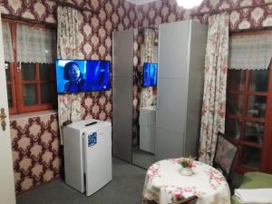 a room with a tv on the wall and a table at Ilona Kis Kastély Panzió in Keszthely