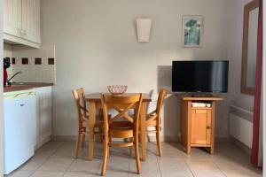 cocina con mesa con sillas y TV en Studio lumineux idéalement situé (golf et plage)., en Moliets-et-Maa