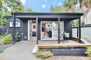 cobertizo negro con terraza y mesa en Aspen Studio - Christchurch Holiday Homes en Christchurch